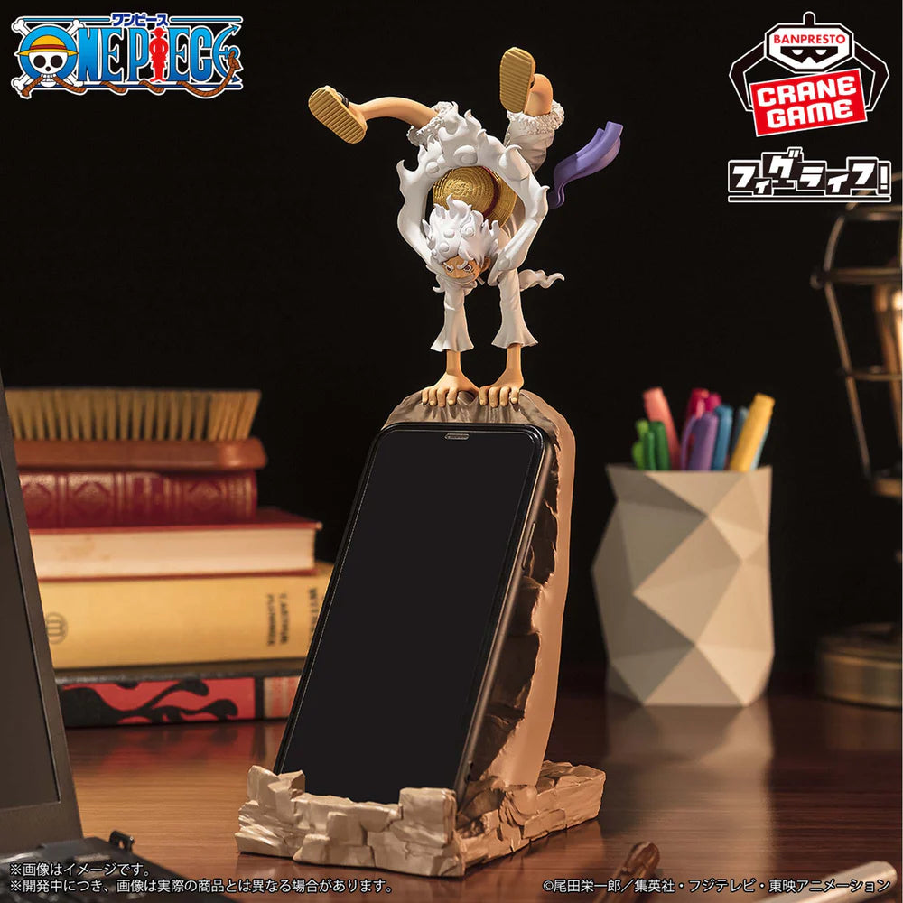 Phone stand with figurine on top, featuring anime branding, on a desk.