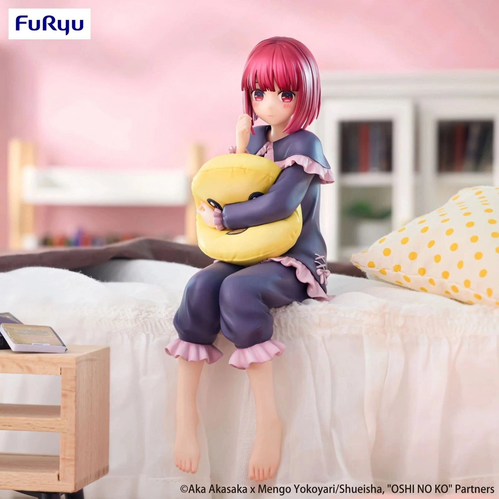 Anime figurine of a character with pink hair sitting on a bed holding a yellow cushion, with 'Furyu' branding.