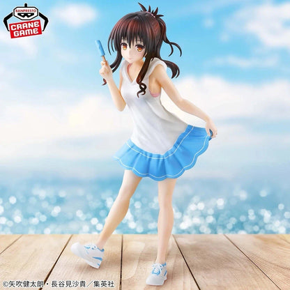 Anime character figurine in a white top and blue skirt against a blurred beach background