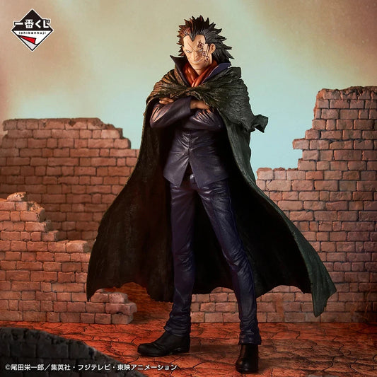 A collectible action figure/statue of a spiky-haired male character in a dark coat and black outfit, posed with arms crossed in front of a ruined brick wall backdrop. The figure is shown against a stylized painted background with a logo in the top-left corner.